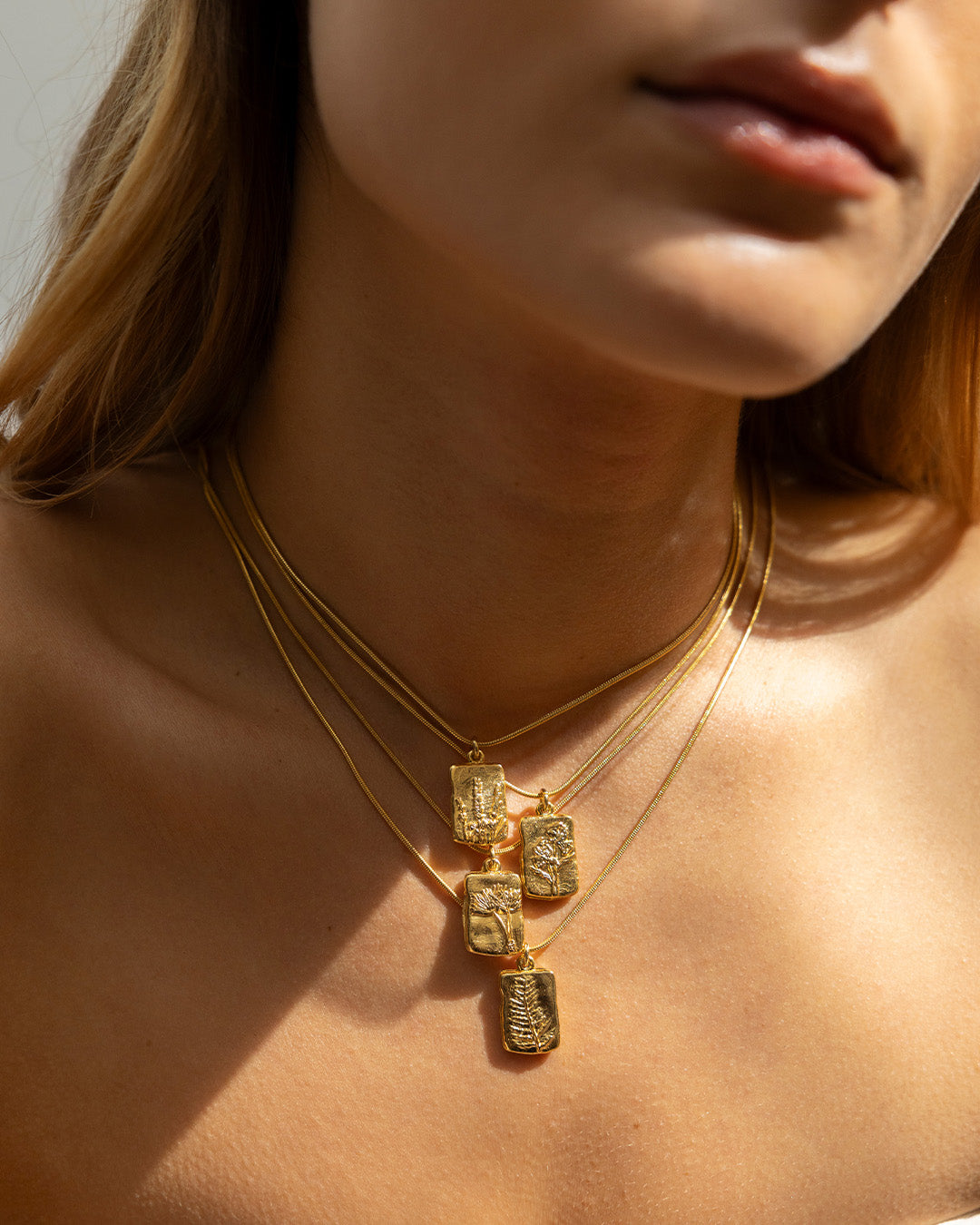 Cuello de mujer luciendo los collares Amuletos diente de león, helecho, lavanda, y magnolia