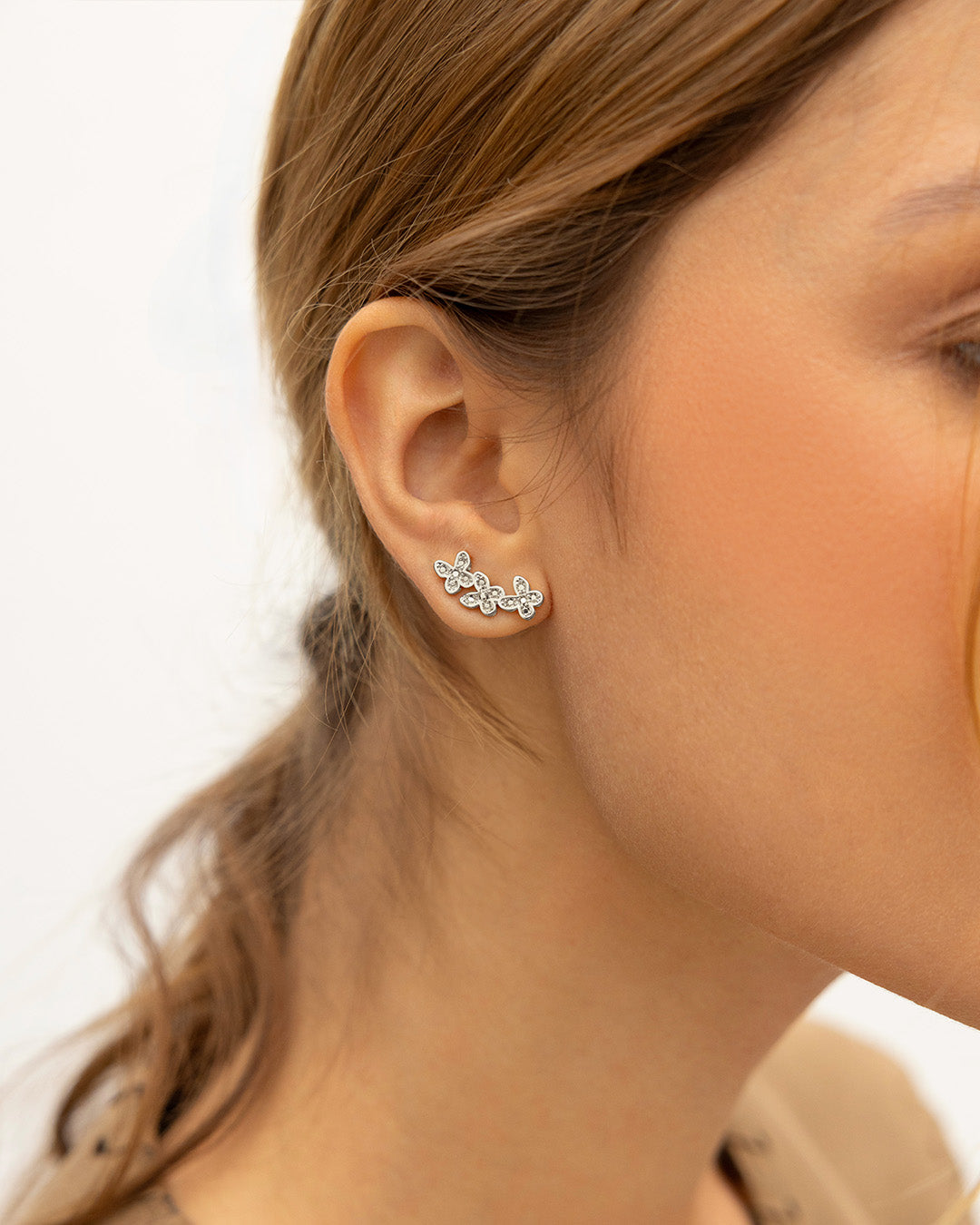 Mujer de perfil luciendo los aretes Encanto con tres mini mariposas